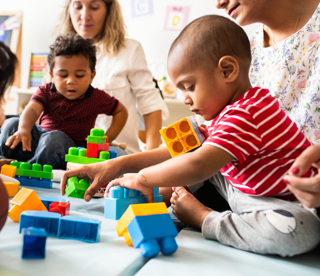 Bébés et bambins entrain de jouer dans une crèche avec des adultes